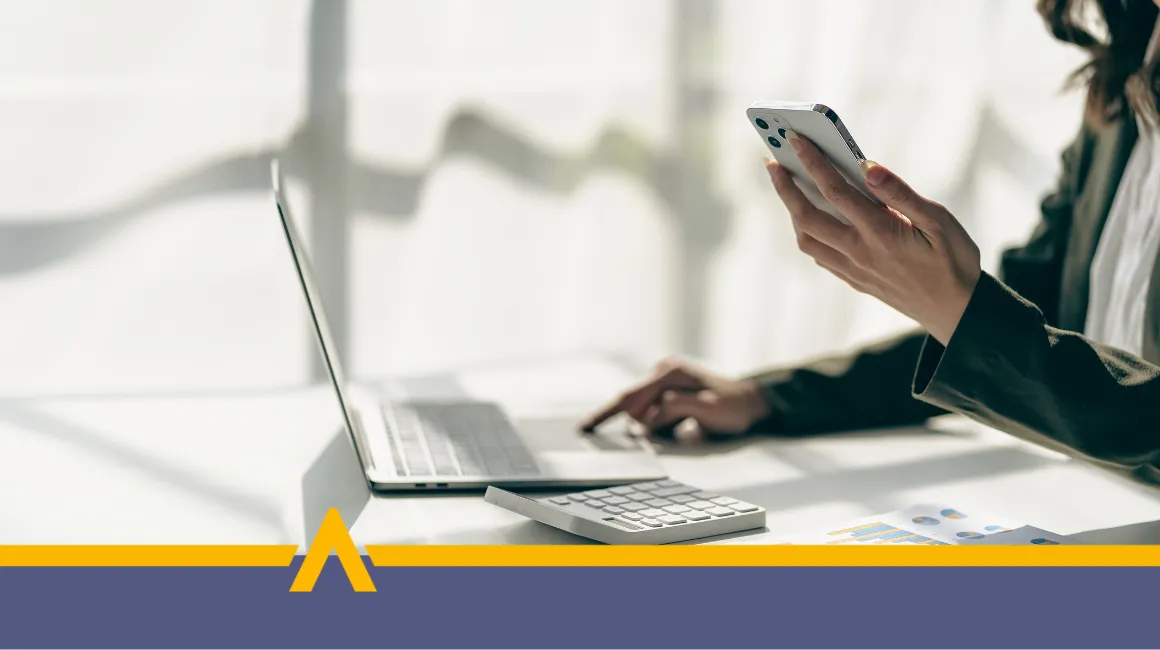 Kobieta korzystająca z laptopa i smartfona w jasnym biurze